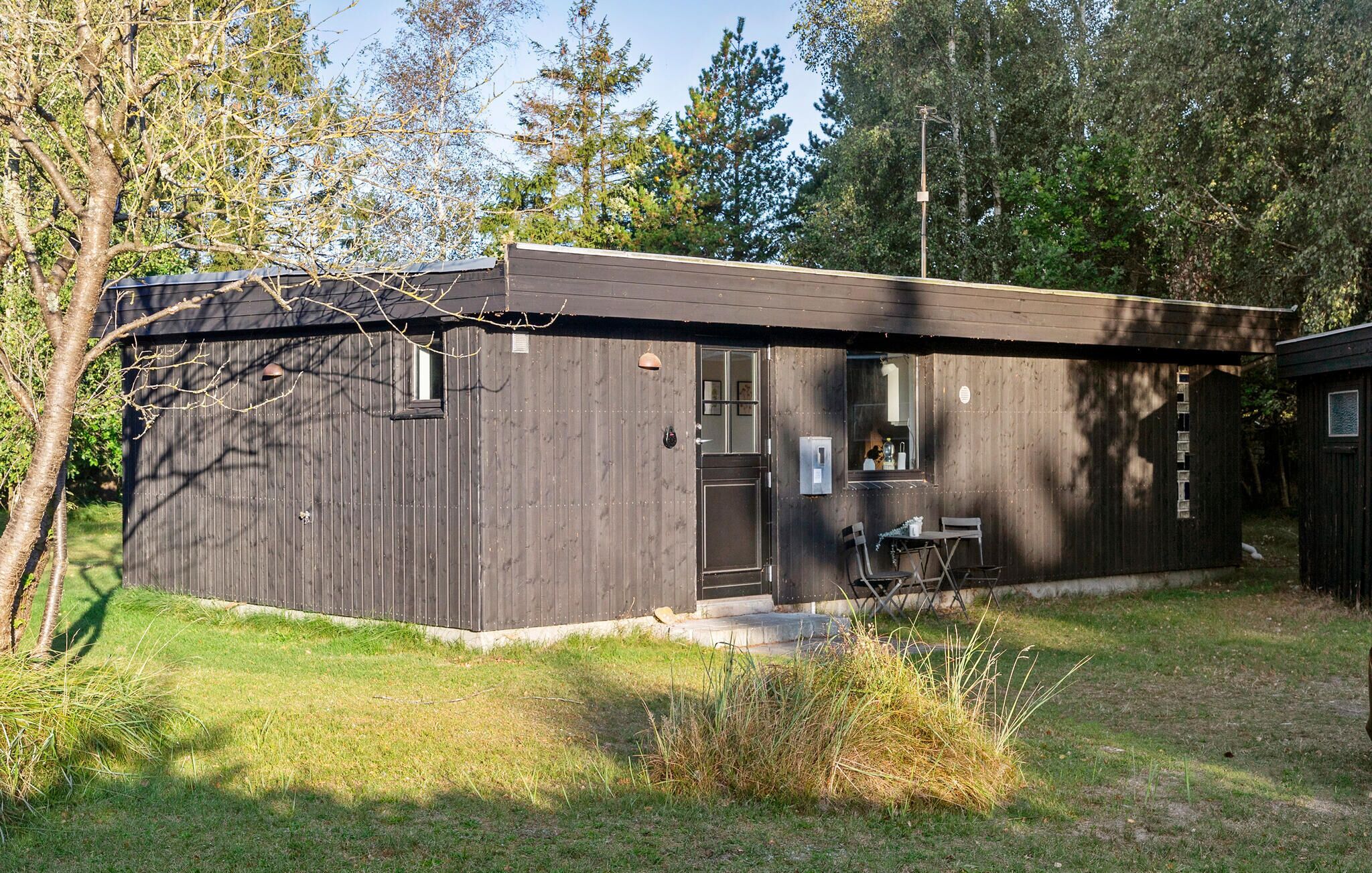 A small, single-story wooden cabin with a dark brown exterior, a front door, and a small porch area.