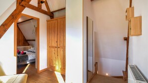 Una habitación con techo inclinado, vigas de madera, una cama con ropa de cama estampada, un armario y un radiador.
