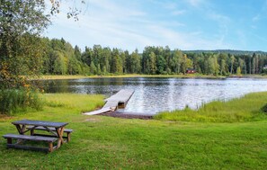 A lakeside picnic area with a wooden dock extending into the water, surrounded by lush greenery and a forest in the background. - 2 bedroom amazing home in Töcksfors (Töcksfors)