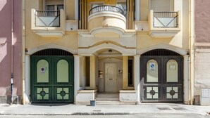 A building with a central entrance, two balconies, and a door with a sign. - GuestHost - Spacious apartment of about 100 sqm, ideal for groups or families of up to 6 guests, located on the third floor of a building with an elevator (NOT for disabled persons). The property is situated in the residential district of La Vega, a quie (Cagliari)