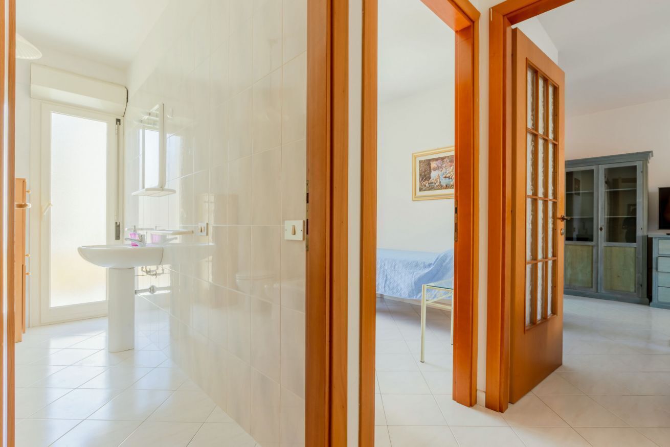 A room with a bed, a wooden door, a cabinet, and a window.