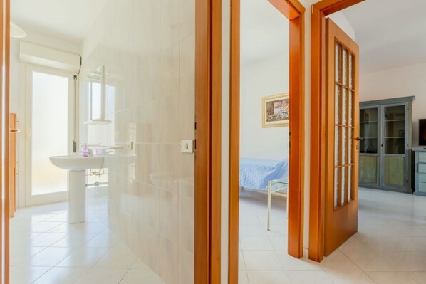 A room with a bed, a wooden door, a cabinet, and a window.
