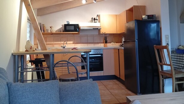 A compact kitchen with a microwave, stove, refrigerator, and wooden cabinets. - Apartment 'Casa Sabine' in Freiburg im Breisgau at Tuniberg with Mountain View and Wi-Fi (Freiburg)