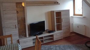 A room with a television on a wooden stand, a window with a view, and a radiator. - Apartment 'Casa Sabine' in Freiburg im Breisgau at Tuniberg with Mountain View and Wi-Fi (Freiburg)