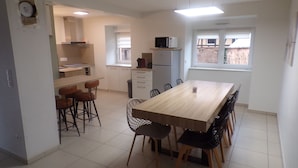 Cozinha moderna com armários brancos, uma mesa de jantar com cadeiras e uma janela com vista para o exterior.