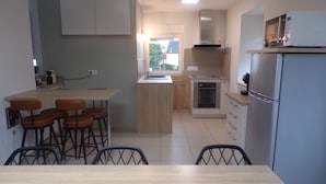 Cozinha moderna com ilha central, banquetas, forno embutido e geladeira.