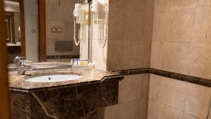 Un baño con lavamanos de mármol, un espejo y un inodoro.