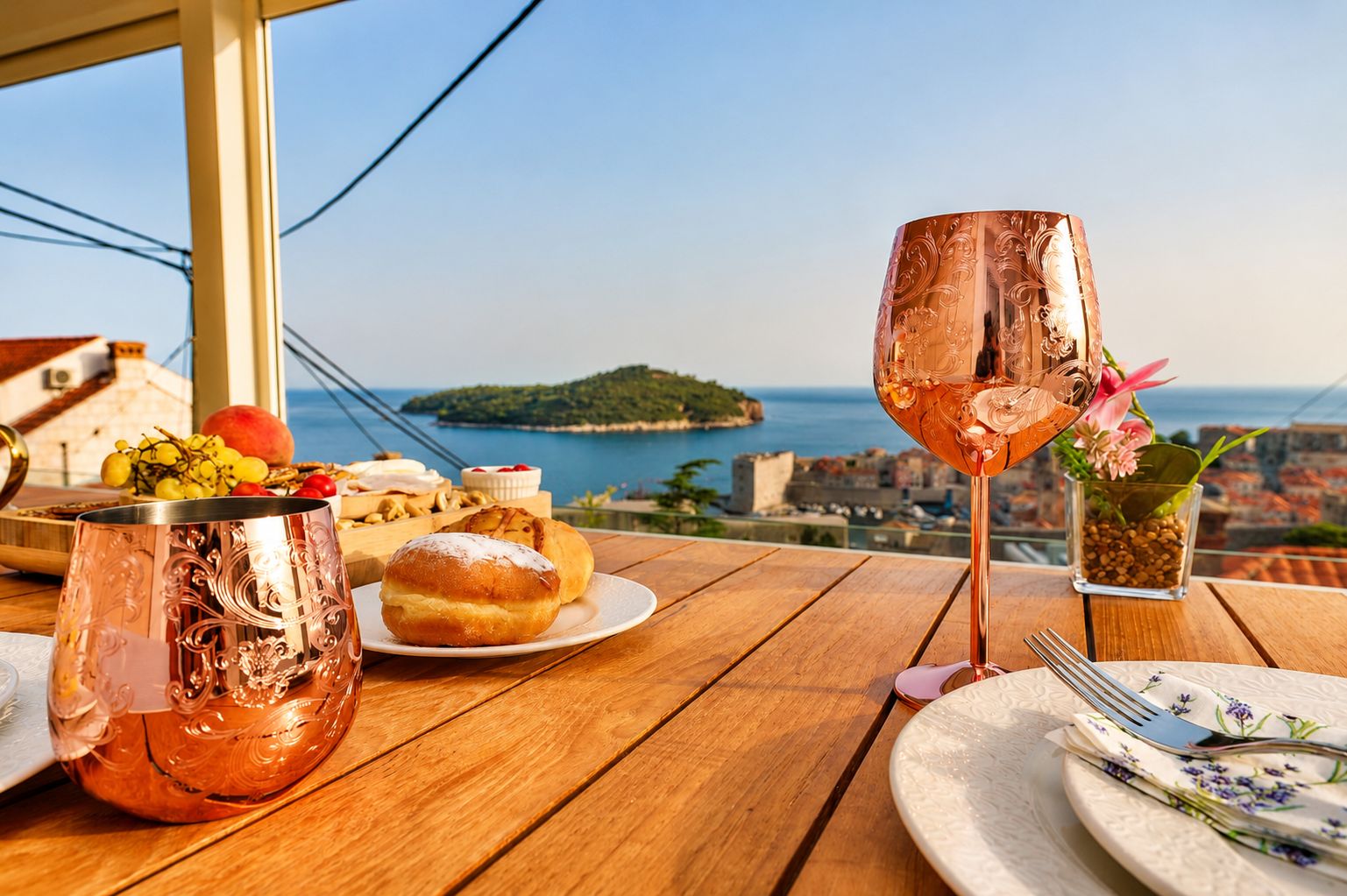 Ein Tisch mit einer Kupferkanne, einem Getränk, Gebäck und Blick aufs Meer.