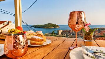 Ein Tisch mit einer Kupferkanne, einem Getränk, Gebäck und Blick aufs Meer.