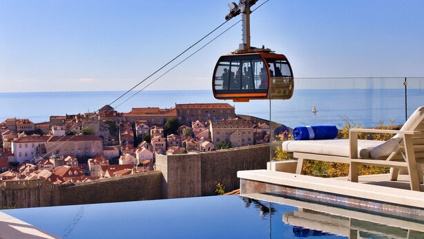 A cable car over a pool with a city view.