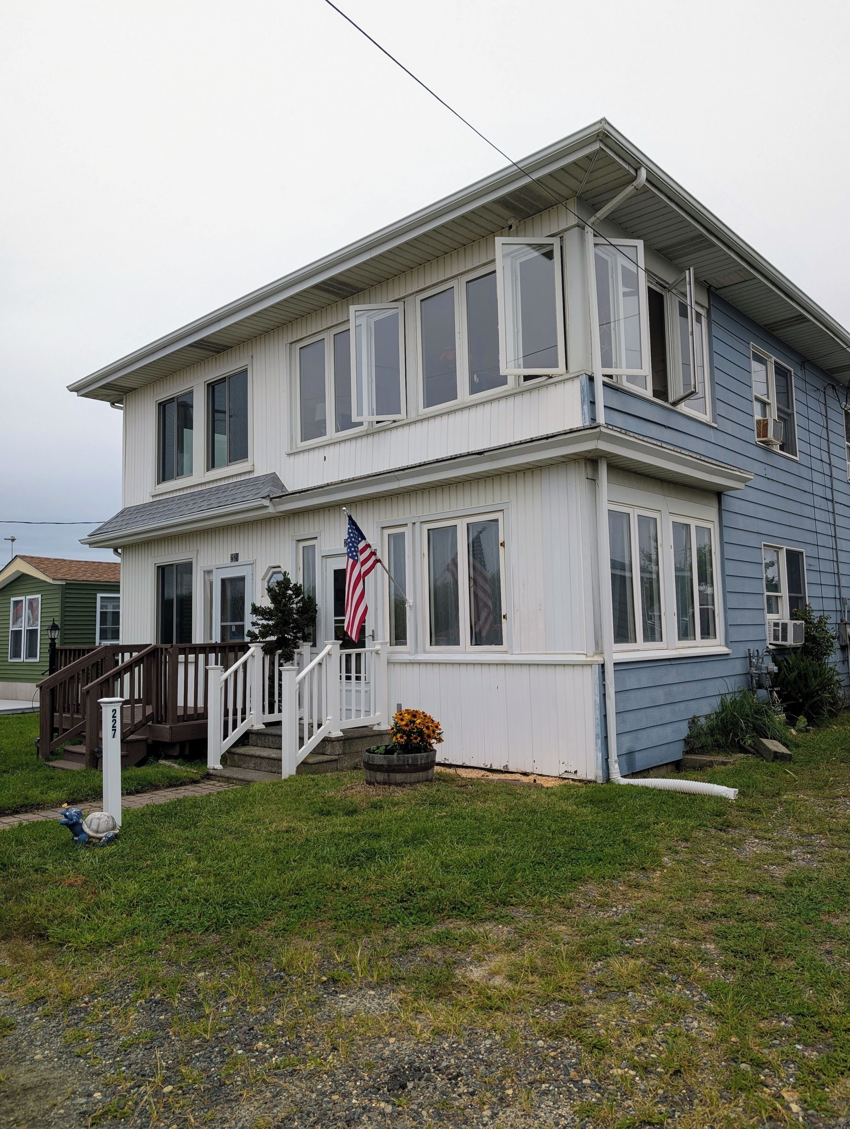 A two-story house with a front porch, a flag, and a mailbox.