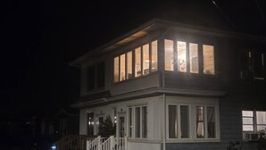 Ein zweistöckiges Haus mit einem markanten Obergeschoss und großen Fenstern.