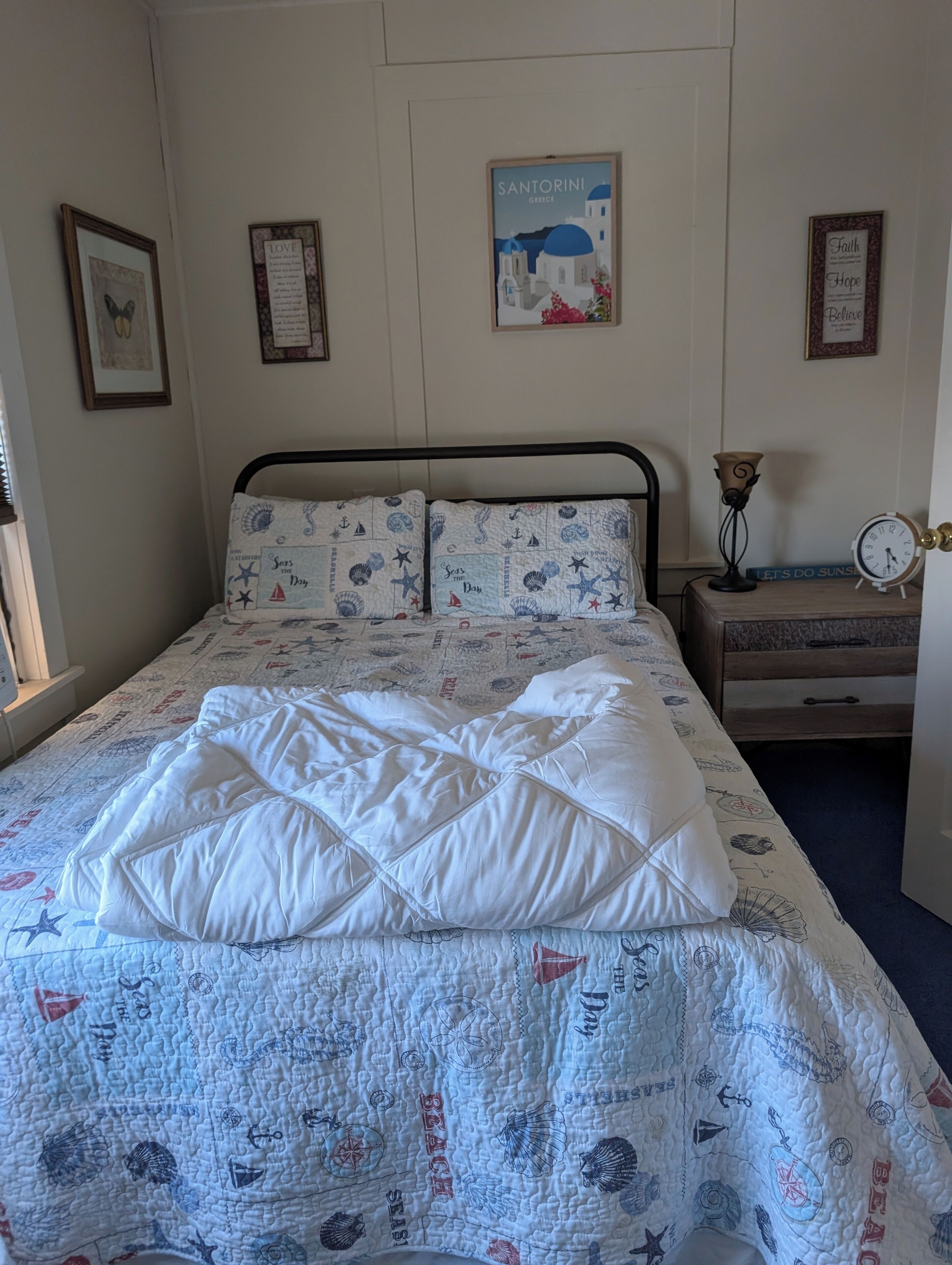 Une chambre à coucher avec un lit, une table de chevet, une horloge murale et des tableaux encadrés.