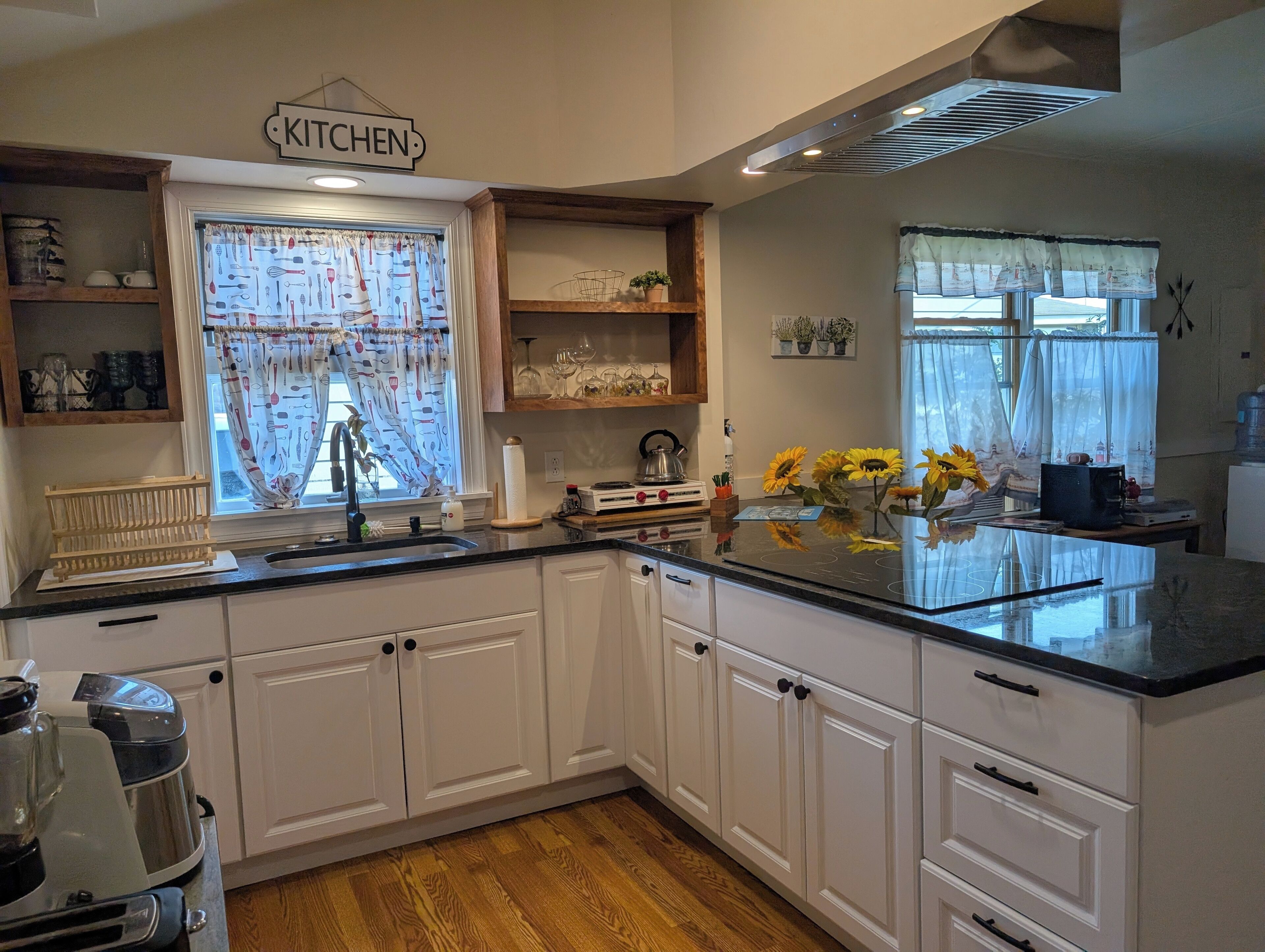 Una cocina con armarios blancos, encimera negra y un letrero que dice 'KITCHEN'.