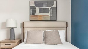 A neatly made bed with two pillows, a bedside lamp, and a framed abstract artwork above it. - Landing | Stylish 1BD, Gym (Dunedin)