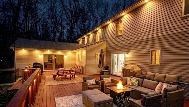 Um deck de madeira com móveis de exterior, uma lareira e um espaço coberto para sentar.