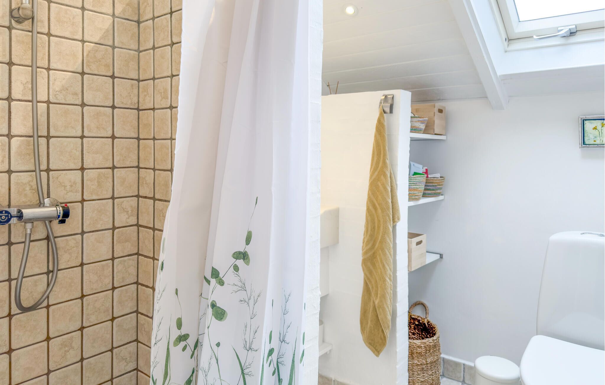 A bathroom with a shower, a toilet, and a shelf with toiletries.