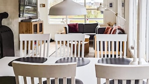Una sala de estar moderna con muebles blancos, un ventanal y vistas al exterior.