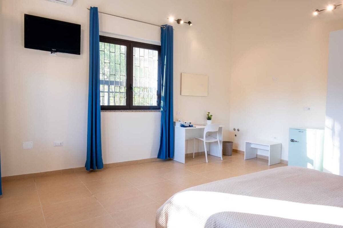 Ein Schlafzimmer mit Bett, Schreibtisch, Stuhl und einem kleinen Kühlschrank.