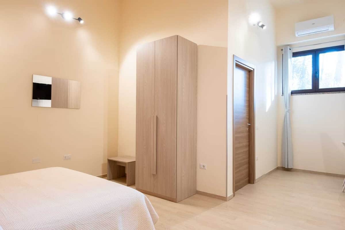 Ein Schlafzimmer mit Bett, Kleiderschrank und einem fenster mit Vorhängen.