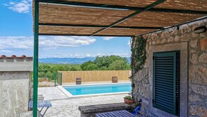 Ett poolområde med en stenmur och en träpergola.