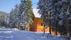 Eine Holzhütte, umgeben von schneebedeckten Bäumen.