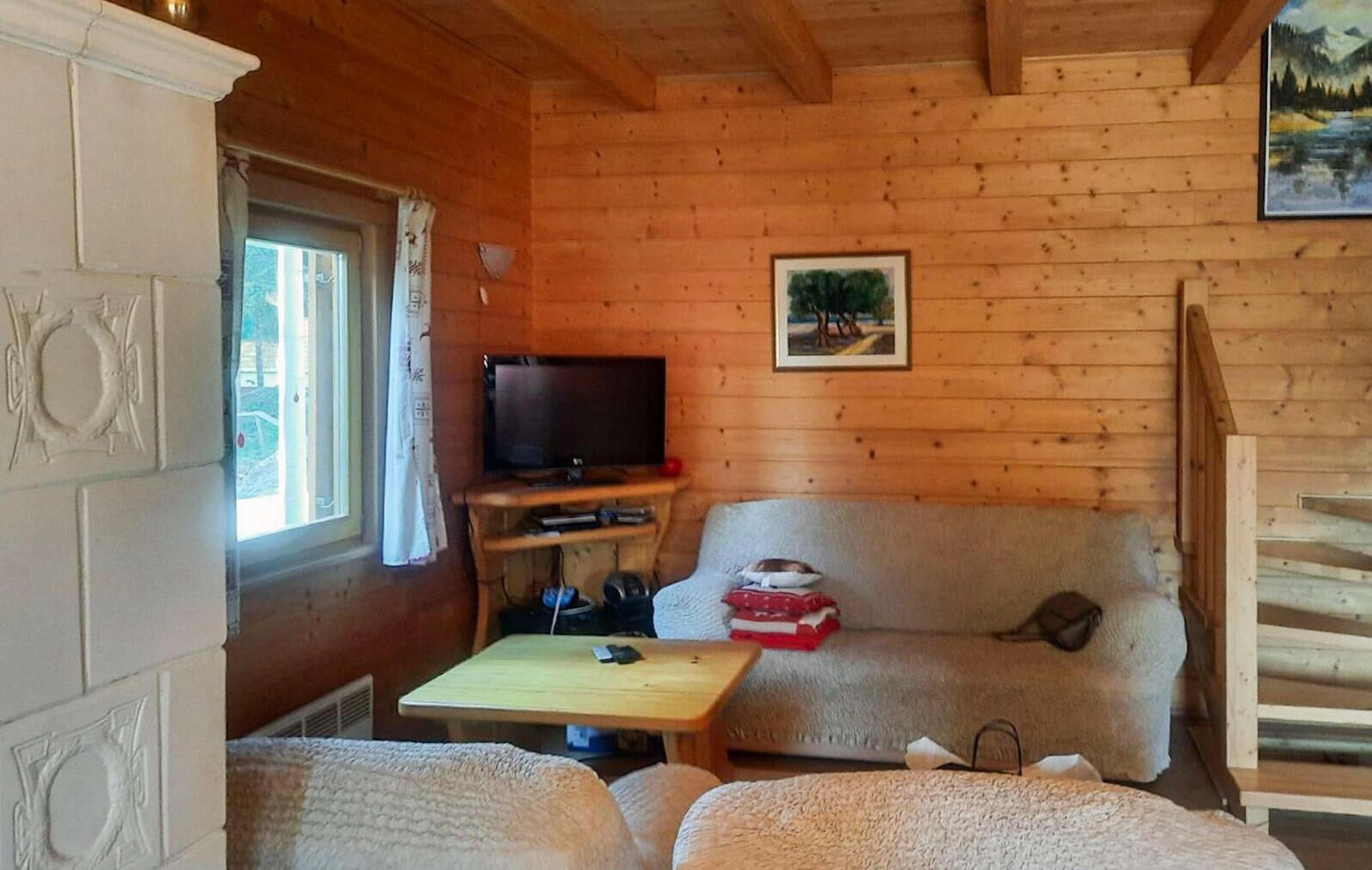 Ein gemütliches Blockhaus-Interieur mit Holzausstattung, einem Fernseher auf einem Schrank, einer Couch und einem kleinen Tisch.