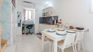 A compact kitchen with white cabinets, a marble backsplash, and a dining area with white chairs and a table set for four. - Casa Matiri by Wonderful Italy (Catania)