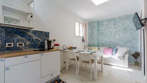 A modern kitchen with white cabinets, a marble backsplash, and a dining area with a white table and chairs. - Casa Matiri by Wonderful Italy (Catania)