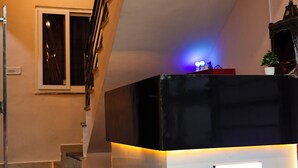 A reception desk with a sign reading "SSD" in a modern lobby with a staircase and a window. - Hotel Saraswati Stay Dham (Vrindavan)