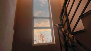 A staircase with a view of a cityscape through a window. - Hotel Saraswati Stay Dham (Vrindavan)