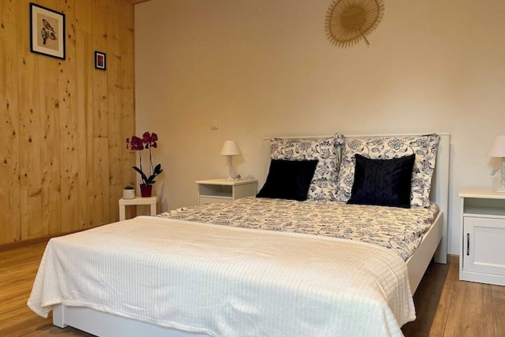 A bedroom with a bed, nightstands, a lamp, and a wall-mounted decorative item.