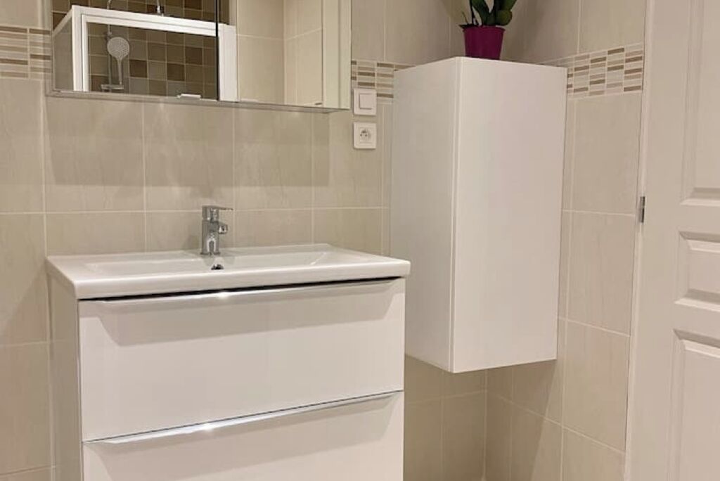 A bathroom with a white sink, a mirror, and a cabinet.