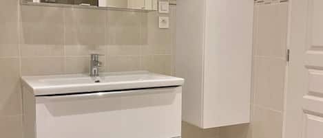 A bathroom with a white sink, a mirror, and a cabinet.