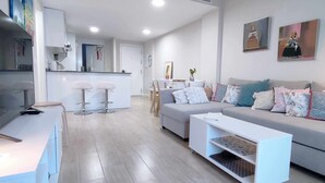 Ein modernes Wohnzimmer mit einem grauen Sofa, weißen Barhocker und einem Couchtisch.