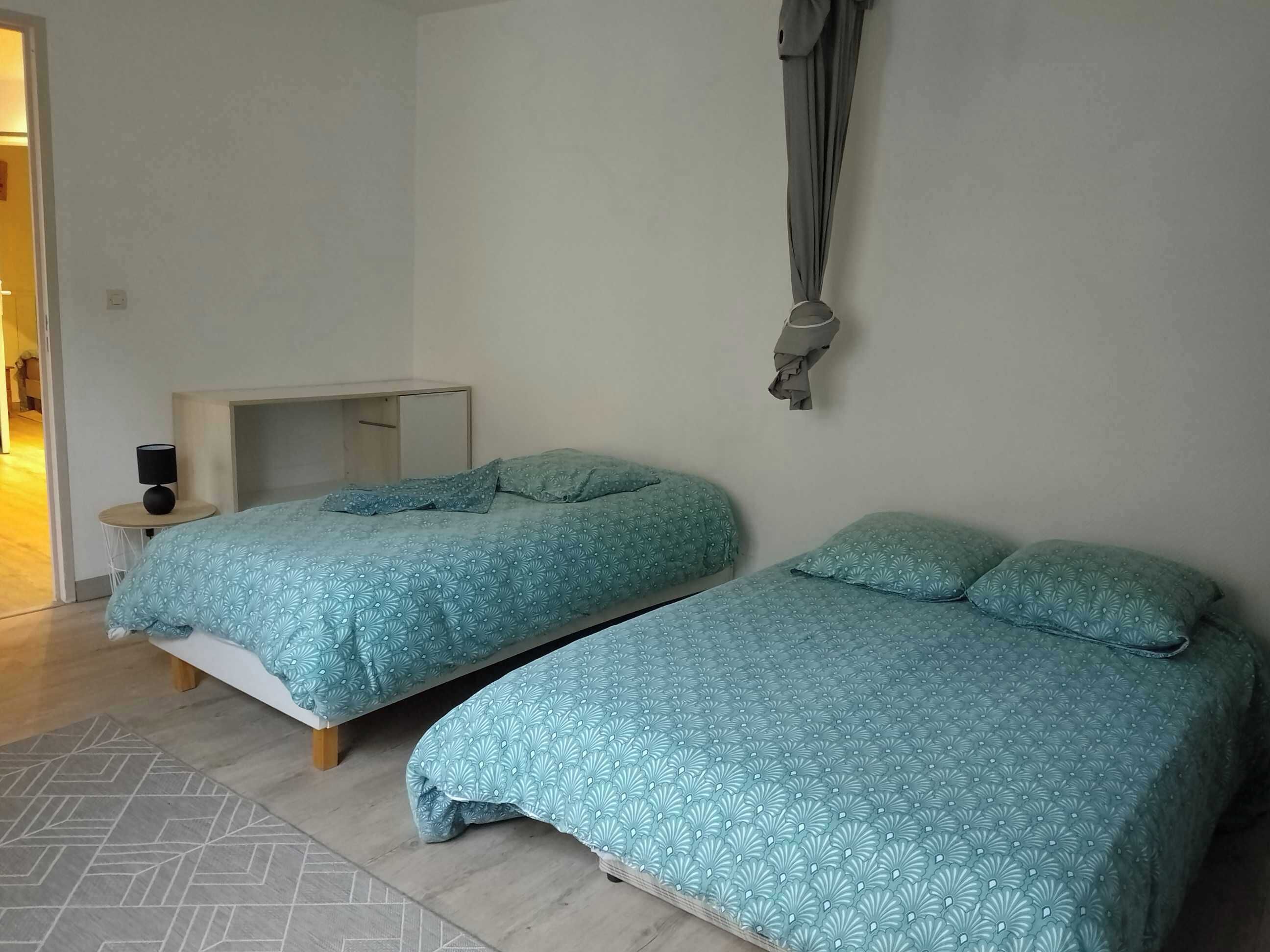 A bedroom with two beds, a desk, and a hanging chair.