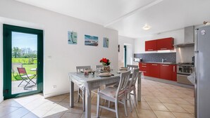 Una cocina moderna con armarios rojos, un refrigerador de acero inoxidable y un comedor con mesa y sillas.