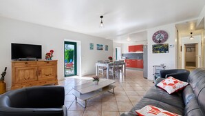 Una sala moderna con televisor de pantalla plana, un mueble de madera, un sofá de cuero y un comedor con mesa y sillas.