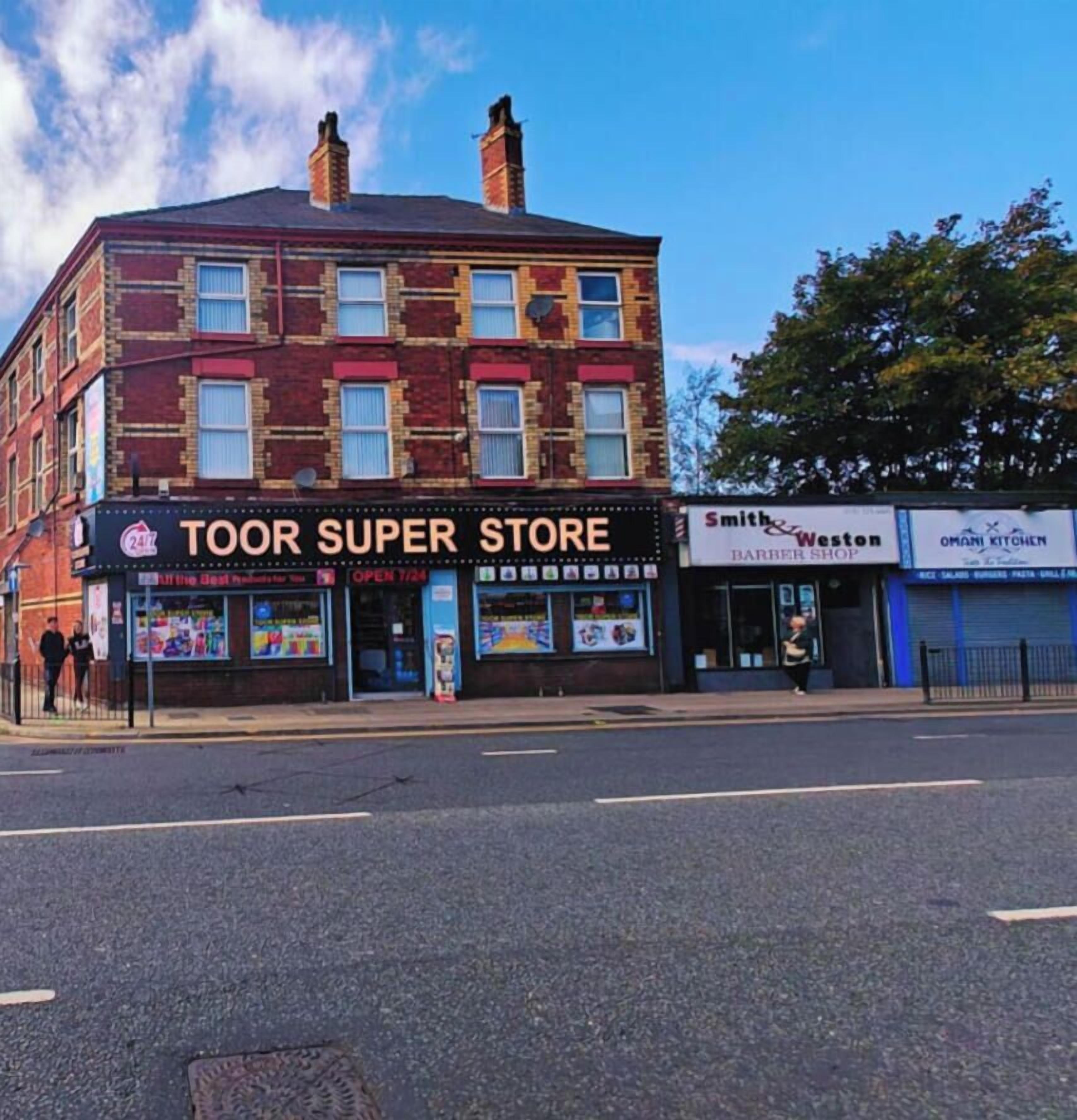 A multi-story building with a storefront labeled "TOOR SUPER STORE" and adjacent shops including "Smith & Weston BARBER SHOP" and "OMANI KITCHEN".