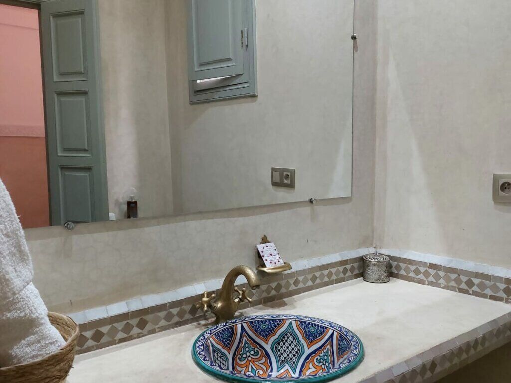 A bathroom with a sink, a decorative plate, a towel, and a mirror.