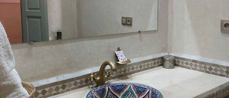 A bathroom with a sink, a decorative plate, a towel, and a mirror.