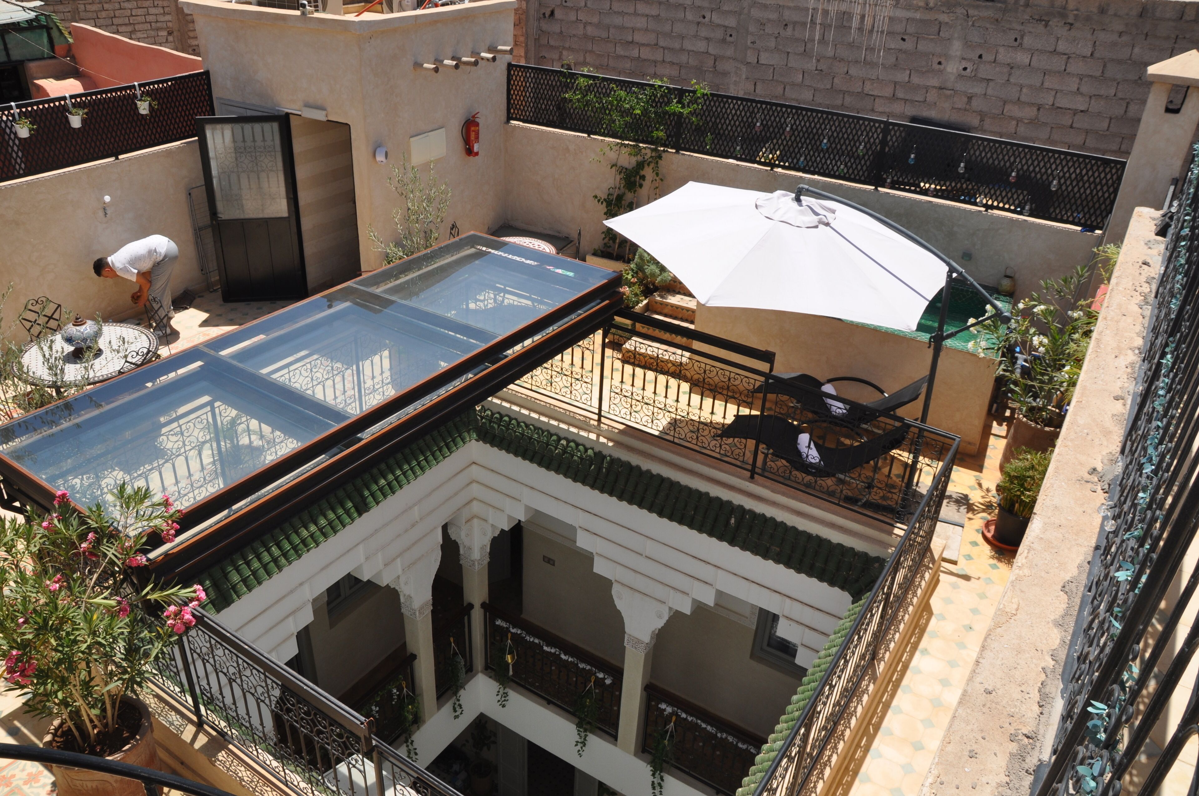 A rooftop terrace with a glass enclosure, outdoor seating, and a potted plant.