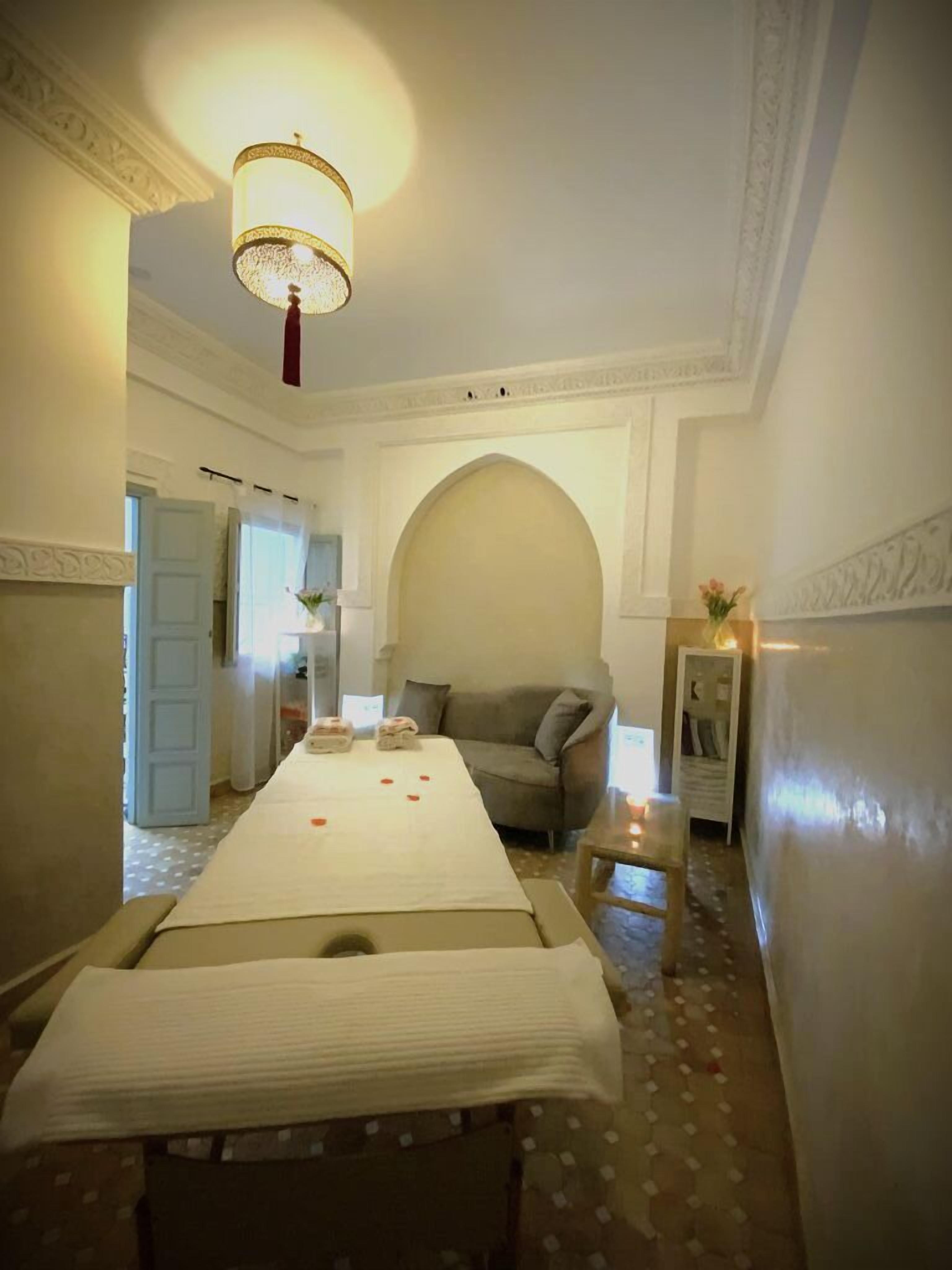 Una habitación de hotel con una cama grande, un sofá, una mesita y una lámpara decorativa.