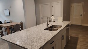Una cucina moderna con piani in granito, lavello in acciaio inossidabile e pensili in legno.