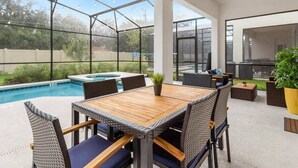 Un patio extérieur couvert avec une piscine, une table à manger et des chaises.