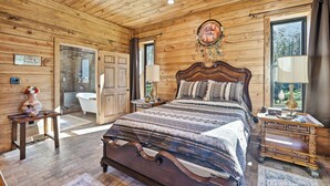 Une chambre située dans une cabane en bois, avec un grand lit, une coiffeuse et une salle de bain.