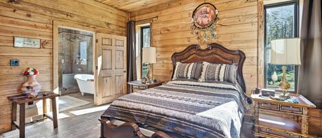 A wooden cabin bedroom with a large bed, a vanity, and a bathroom.
