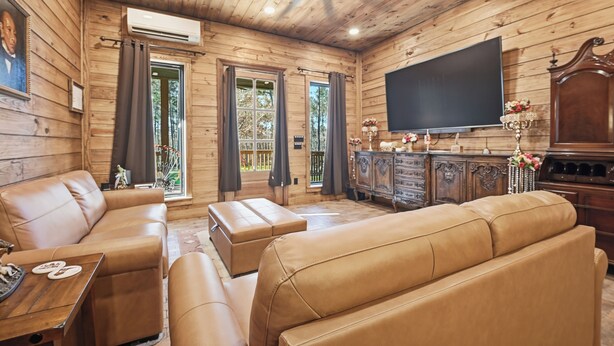Un intérieur en bois avec des canapés en cuir, un téléviseur à écran plat et un meuble contenant des objets décoratifs.
