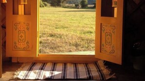 An open wooden door with a view of a grassy field and a tree, leading to a mountain in the distance. - Les insolites de la bastide (La Bastide)