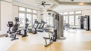 Een ruime fitnessruimte met loopbanden, elliptische trainers en gewichten.